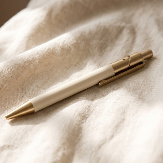 Stylo Clarté, corps crème mat et laiton brossé, posé sur du lin